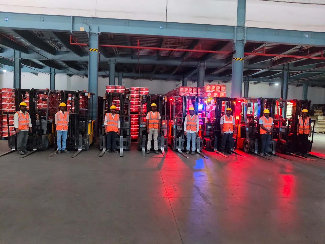 Line of forklift operators in safety vests inside a warehouse